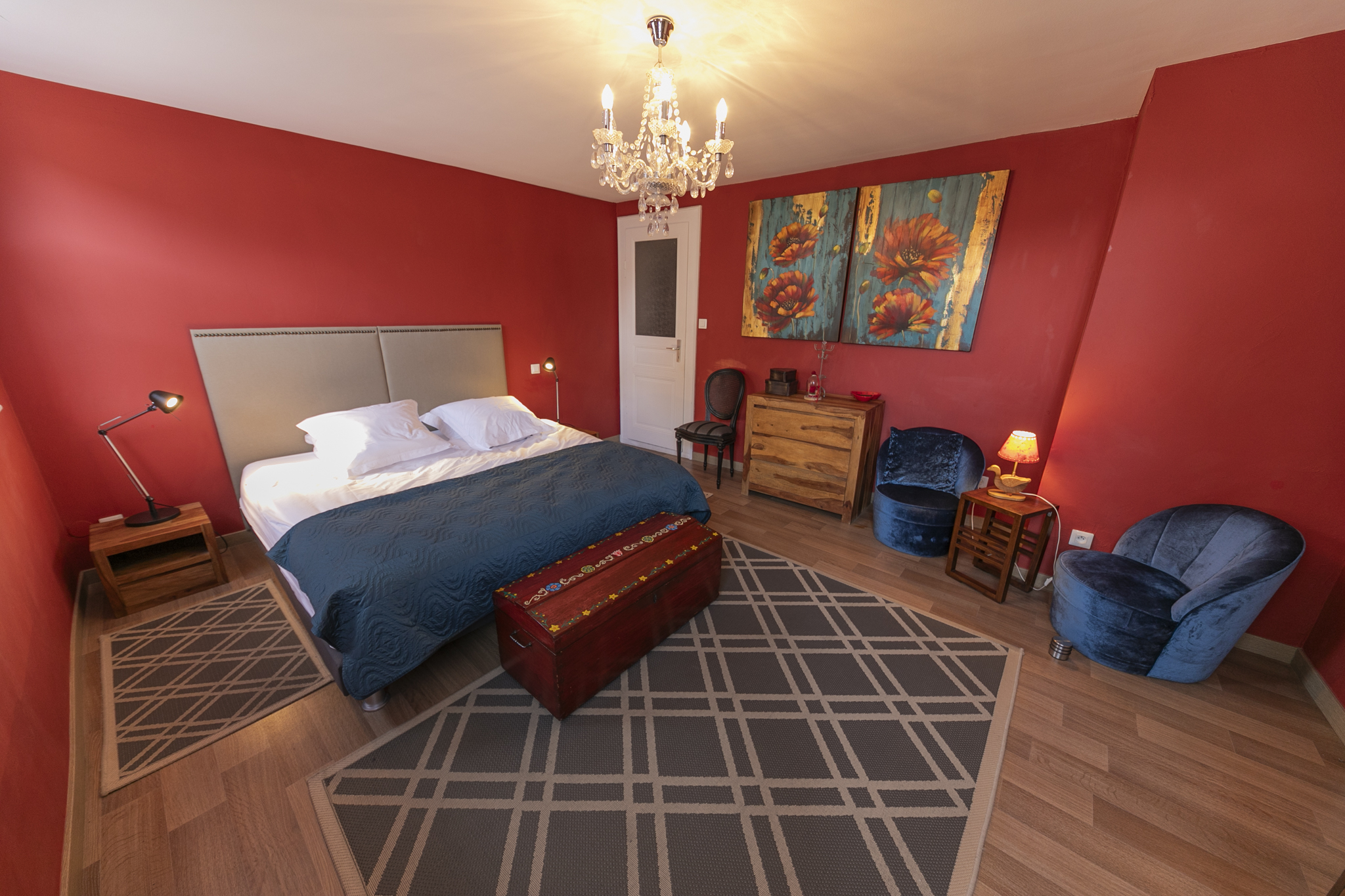 Chambre avec lit king size, murs rouges et lustre