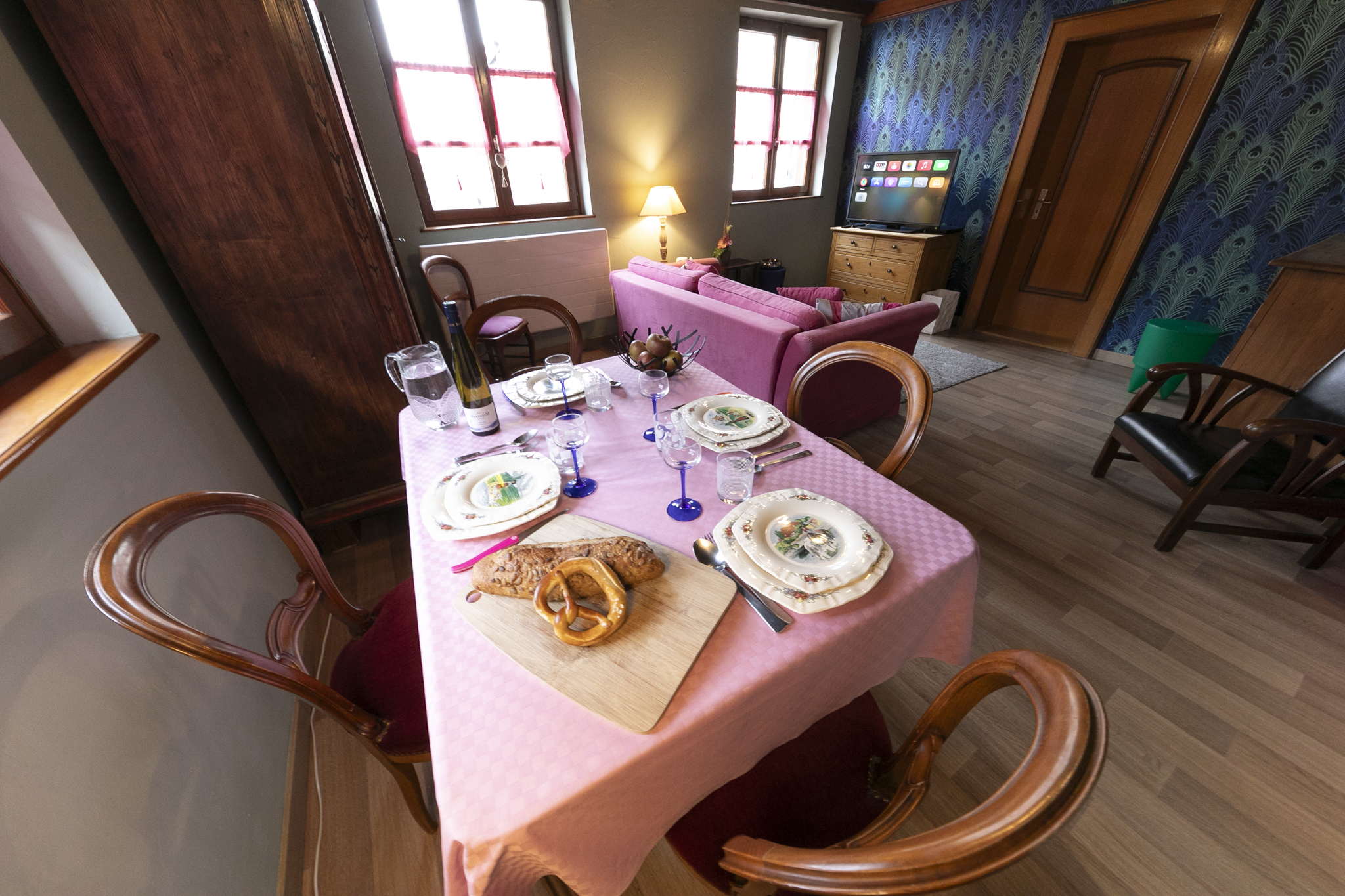 Table dressée avec vaisselle, pain et bretzel, salon en arrière-plan